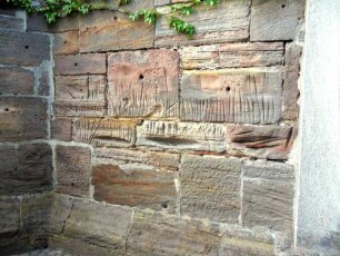 Freienhagen-(Evangelische Kirche) - Kirchturm von Süden - Erdgeschoß im Südsüdwesten-Wetzrillen im Werkstein (symbolisches Entschärfen der Dolche)