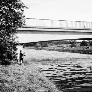 Trave: im Vordergrund links angelndes Kind: dahinter Baum: oben Brücke: im HIntergrund Wiesen mit Rinderherde