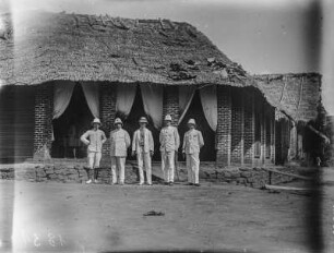 Gruppenbildnis : Gruppenportrait der Expeditionsteilnehmer vor einem Haus