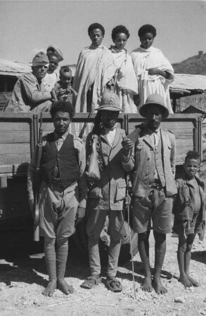 Personen bei einem Lastkraftwagen : Aufnahme eines Mannes der Amhara, der im italienischen Militärdienst steht sowie Frauen der Amhara auf einem Lastkraftwagen in Burka.