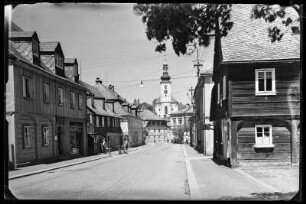 Schönlinde (Krasna Lipa/Tschechische Republik). Straße mit Umgebindehäusern. Blick zur Pfarrkirche St. Magdalena