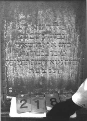Grabstein 218 (Index: 99608942) Material: Sandstein Zustand: sehr stark verwittert im oberen Teil mit Textverlust Maße HxBxT: 118x65x20 cm Beschreibung: Stele, profilierter Sockel, eingezogener Rundbogenabschluß mit aufgesetzten Zweigen, Schriftfeld eingetieft: Grabstein 218A