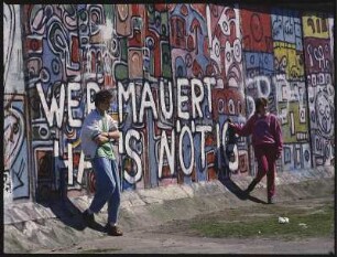Berlin-West. Potsdamer Platz, Grenzanlage Berliner Mauer. Bemaltes Mauerstück mit posierenden Jugendlichen vor dem Spruch "Wer mauert, hat's nötig"