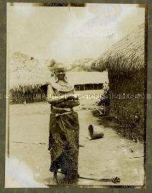 Massai-Frau auf einem Dorfplatz neben einer Hütte