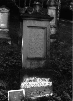 Grabstein 47 (Index: 100101023) Material: Sandstein, neue schwarze Platte Zustand: Schrifttafel fehlt, Sockel verwittert Maße HxBxT: 160x45x21 cm Beschreibung: Stele, Sockel, Abdeckplatte mit rechteckigem Aufsatz und seitlichen Voluten, eingetieftes Schriftfeld rechteckig Symbolik: Voluten Besonderheit: eingemeißelte Nummer: 34: Grabstein 47