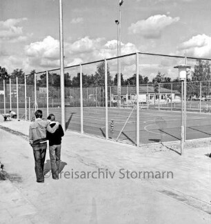 Sporteinrichtungen: Sportanlage am Kortenkamp: Kleinspielfeld nach Fertigstellung: links zwei Schüler: dahinter Arbeiter an Maschendrahtzaun beim Setzen eines Steines: daneben Schubkarre: hinten rechts Sportlerheim: hinten links Wohnhäuser: dahinter Bäume