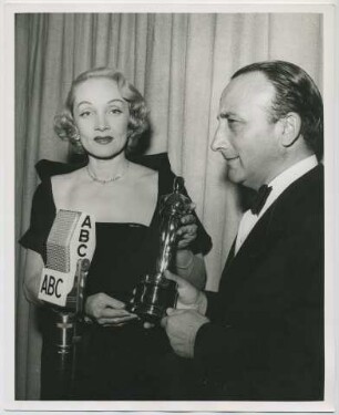 Marlene Dietrich überreicht dem Italienischen Konsul Dr. Mario Ungaro den Oscar für "Die Mauern von Malapaga" (mit Jean Gabin) als bestem fremdsprachigen Film (Los Angeles, März 1951) (Archivtitel)