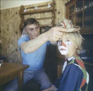 Zirkus Kaiser. Der Sohn des Zirkusdirektors wird von seinem Vater als Clown August geschminkt und verkleidet