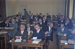 Kreistagssitzung: Kreisberufsschule [Bad Oldesloe]: Grabauer Straße / Ecke Lorentzenstraße: Aula: Kreistagsmitglieder an Schulbänken, darunter Gertrud Lege