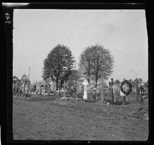 [Bailleul-Sir-Berthoult (Dep. Pas-de-Calais, Frankreich):] unbefestigte Soldatengräber mit Grabkreuzen und einer innenliegenden, von Bäumen umgebenen Friedhofskapelle in einer morastigen Landschaft
