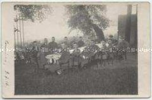 Fotopostkarte mit einem Gruppenfoto von Militärangehörigen an einer Festtafel mit rückseitigem Text - Personenkonvolut
