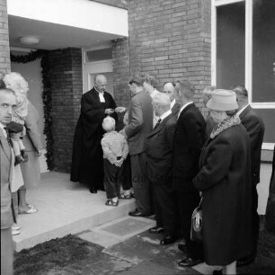 Evangelische Kirchengemeinde Reinfeld: Eichberg-Pastorat: Eichbergstraße: Einweihung: vor Haustür: Pastor Gerhard Radtke bei Schlüsselübergabe an Pastor Friedrich Berg, mit Familie: im Beisein von Architekt Franz Möller, Kirchenvorstand, Kirchenältesten, Gästen