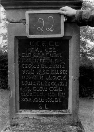 Grabstein 22 (Index: 100107108) Material: Sandstein mit schwarzer Marmorplatte Zustand: Schrifttafel steht auf dem Kopf, mehrfach gesprungen Maße HxBxT: 169x60x32 cm Beschreibung: Stele, getreppter Sockel, Giebel, Schrifttafel rechteckig: Grabstein 22A