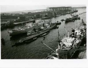 Hamburg. Panoramafotografie eines Teiles des Hafens. Frachtschiffe liegen auf Reede bzw. am Kai und werden entladen