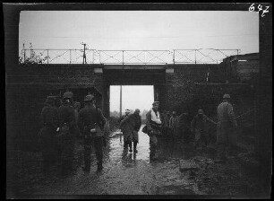 bei Neuville (=Neuville-Saint-Vaast, Dep. Pas-de-Calais, Frankreich): Soldaten mit Pickelhaube neben weiteren Soldaten (französische Kriegsgefangene?) vor einer überfluteten Unterführung