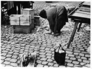 Alte Frau sammelt Marktabfälle