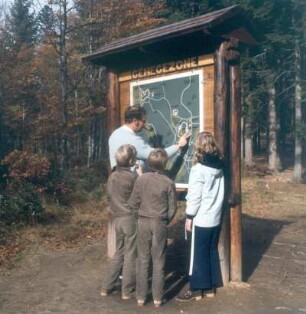 Nationalpark Bayerischer Wald. Erwachsener mit Kindern an einer Informationstafel an einem Rundwanderweg