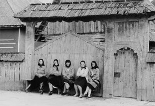 Frauen in Sonntagskleidung vor einem Hoftor