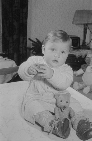 Ein mit Ball und Teddybär spielendes Kleinkind