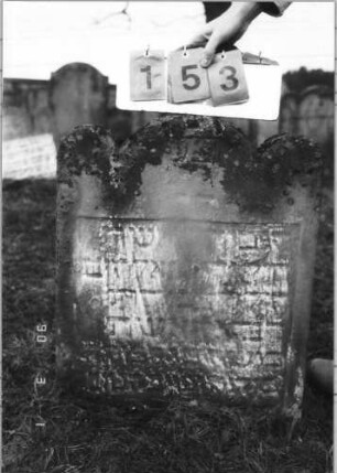 Grabstein 153 (Index: 100114709) Material: Sandstein Zustand: sehr stark verwittert mit großem Textverlust, unterer Teil eingesunken, untere Zeilen eingesunken Maße HxBxT: 64x56x10 cm Beschreibung: Stele mit dreigeteiltem Rundbogen: Grabstein 153