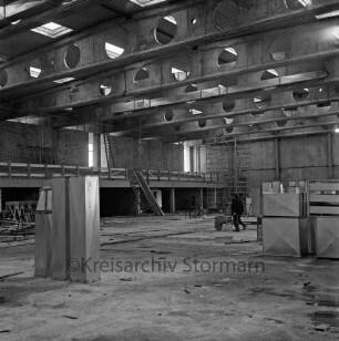 Sporthalle: Neubau: Schulzentrum Glinde: Innenansicht: Rohbau: Blick in die Halle: hinten rechts Arbeiter mit Schubkarre