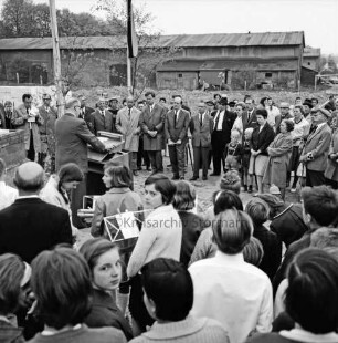 Volksschule Klosterbergen [später: Grundschule Klosterbergen]: Klosterbergenstraße: Neubau: I. Bauabschnitt: Grundsteinlegung: Rede von Bürgermeister Hermann Körner: vorn und hinten Vertreter der Stadt, Schüler, Lehrer und Gäste: im Hintergrund Ställe des ehemaligen Gutshofes Schaumann