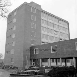 Erweiterungsbau "Hochhaus" vor Einweihung [später Gebäude B]: III. Bauabschnitt: rechts Verbindungstrakt zum Hauptgebäude [später Gebäude A]: vorn Erdhaufen und Stapel mit Gehwegplatten: in der Mitte Arbeiter: Blick von Innenhof