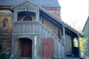 Kirche: Langhausnordwand mit überdachtem Emporenaufgang und Rundbogenfenster
