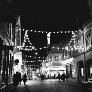 Mühlenstraße mit Adventsbeleuchtung: Passanten und parkende Pkw, links das Kaufhaus Nickel, rechts Einmündung der Hindenburgstraße, Blick Richtung Süden
