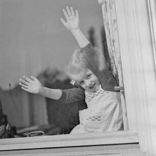 Ein Mädchen mit Zöpfen und Schleifen am Fenster