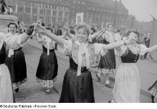 Frauengruppe in Trachtenkleidung im Demonstrationszug beim Vorbeimarsch an der Ehrentribüne auf dem Karl-Marx-Platz (heute: Augustusplatz), im Hintergrund das Kroch-Hochhaus