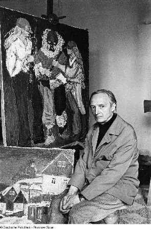Der Maler Theodor Rosenhauer mit zweien seiner Werke ("Rathen im Winter", 1965, 80 x 105 cm; darüber vermutlich "Drei Schauspieler von der Landesbühne", um 1970, 146 x 122 cm), aufgenommen in Radebeul