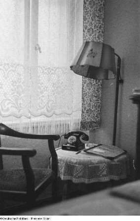 Blick in eine Zimmerecke mit einer Stehlampe und einem Telefon auf einem Beistelltisch