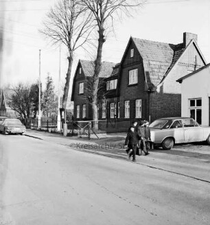 Amtshaus: davor Bäume: im Vordergrund Straße: hinten links Pkw: rechts Gruppe Schulkinder: dahinter parkender Pkw