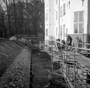 Restaurierung: Arbeiten an Fundament: Gerüst, Arbeiter: innerer Graben: neue Grabenversteifung mit Holzbohlen am Grabenfuß: hinten Arbeiter bei Befestigung der Grabenböschung mit den alten Findlingen: im Hintergrund kleine Parkbrücke über äußeren Schlossgraben