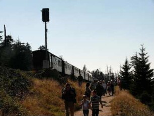 Brockenwanderer und vom Brocken talwärts fahrende Harzer Schmalspurbahn