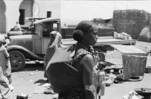 Am Markt : Portrait einer Frau auf dem Markt von Harar, im Hintergrund Händler und Lastwagen.