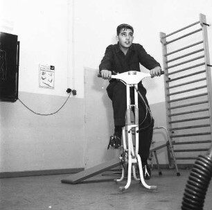 Lehrling während des Sportunterrichtes auf einem Ergometer