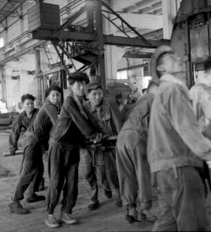 Wuhan (China). Werkhalle, Gruppe von Arbeitern mit einer Stange