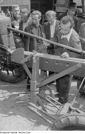 Ausstellungsbesucher an einem landwirtschaftlichen Gerät