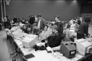 Stormarner Computer-Party "Copy-Inferno": Sporthalle der Joachim-Mähl-Schule: Jugendliche an Computern auf zusammengestellten Tischen: dazwischen stehende Jugendliche: 12. Januar 1992