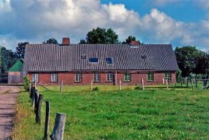 Neverstaven: Landarbeiterkate: Mehrfamilienkate aus Backstein, Traufseite: vorne Weide, Zäune, links Weg, hinten links Bretterscheune