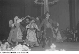 Tanzende Menschen in Tracht bei einer Veranstaltung zum Gedenken an die Völkerschlacht, im Hintergrund ein Maibaum und ein Orchester