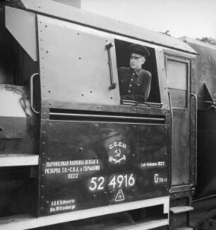 Führerhaus der Güterzug-Lokomotive 52 4916 der Deutschen Reichsbahn (Kriegslokomotive) mit Anschriften in deutsch und russisch mit Bezug auf den Einsatz für die Sowjetische Militäradministration in Deutschland (SMAD). Ansicht der Heizerseite mit Eisenbahner im Fenster