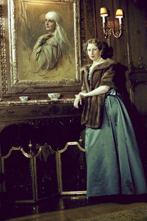 St. Moritz: Prinzessin Ileana von Hohenzollern im blauen Abendkleid; mit Bild von Königin Maria im Hintergrund