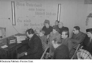 Zuhörer vor dem Radio sitzend
