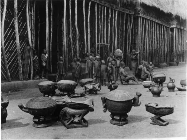 Frauen und Kinder vor dem Häuptlingspalast, davor mehrere Gefäße/ Women and children with multiple containers in front of the royal palace (Foumban).