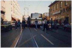 Blick auf eine Straße mit nebeneinander stehender Straßenbahn und Bus (Altersgruppe bis 14)