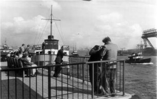 Hamburg-St. Pauli. Besucher schauen sich den Schiffsverkehr auf der Elbe von den Landungsbrücken aus an