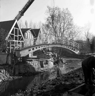 Trave: Stadtarm: Bau der Brücke zwischen der Hude und Heiligengeiststraße: ein Krangerät hebt die Brücke ein, vorne rechts eine Person, rechts Gebäude der Heiligengeiststraße, Blick nach Norden